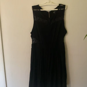 Svart prickig klänning R&D Label - Svart långklänning från R&D Label med transparenta meshpartier upptill och prickigt mönster. Klänningen är ärmlös och har en snygg dragkedja i ryggen. Perfekt för dig som gillar stilrena och coola detaljer.