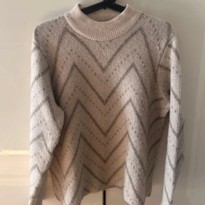 Beige stickad tröja med zigzag-mönster - Mysig stickad tröja från Kappahl. Den är inte mycket använd. Den är tjock o passar perfekt till vinterns kalla dagar 💕hund finns i hemmet 💕nypris 499