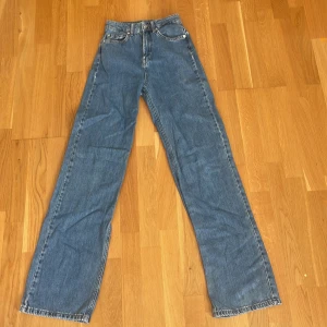 Blå raka jeans från NA-KD, stl 32 - Klassiska blå jeans från NA-KD i rak modell med normal passform. Jeansen har fem fickor, knapp- och dragkedjegylf samt snygga kontrastsömmar. Tillverkade i bomull för en skön och tidlös look. Ord pris 500kr