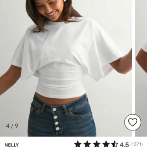 Vit T-shirt med vida ärmar från Nelly - Säljer en vit croppad topp från Nelly med breda, korta ärmar och tight midja. Aldrig använd. 