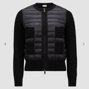 Svart cardigan jacka från Moncler - Buda på min jacka❤️Snygg svart cardigan jacka från Moncler med quiltad front i glansig polyester och stickade ärmar. Jackan har tvåvägsdragkedja och ribbade muddar. Perfekt för lager-på-lager och en clean look.