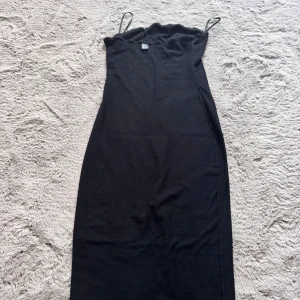 Svart långklänning med smala axelband - En stilren svart långklänning med inga axelband. Klänningen har en enkel och klassisk design som gör den lätt att styla. Köpt från shein använt några par gånger☺️