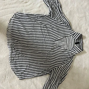 Randig skjorta från H&M Divided - Snygg skjorta från H&M Divided i svartvitt randigt mönster. Skjortan har lång ärm, klassisk krage och avslappnad passform. Perfekt att styla med jeans eller kjol för en cool look. Tillverkad i mjuk bomull som känns skön mot huden.Skickas snabbt och stryks innan leverans om du vill 😉