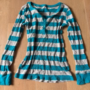 Randig långärmad tröja  - Superskön långärmad tröja med breda turkosa och grå ränder. Tröjan har ribbad matterial. 