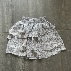 Leopardmönstrad volangkjol från H&M - Supersöt kort volangkjol från H&M med leopardmönster i svart och beige på ljus bakgrund. Kjolen har bred resår i midjan och flera lager volanger som ger en flowy känsla. 