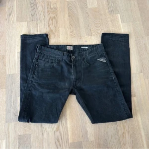 Svarta Replay jeans slim fit - Snygga svarta jeans från replay med klassisk femficksdesign. Byxorna har en knappgylf och bälteshällor, vilket gör dem perfekta för en stilren look. En sjukt underrated modell med galen passform om du frågar mig! Jeansen är nästan helt nya och super sköna! Fråga gärna om ni undrar något eller om ni vill ha fler bilder!