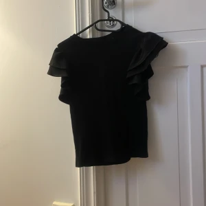 Svart blus med dubbla volangärmar - Svart volang tröja, från Gina Young, med puffiga armar och ribb detaljer. Aldrig använd.