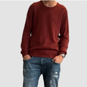 Mörkröd stickad tröja Tiger of Sweden - Säljer en mörkröd stickad tröja från Tiger of Sweden. Tröjan har ett diskret kabelstickat mönster, rund halsringning och långa ärmar. Perfekt för dig som gillar stilrena och klassiska plagg med en modern touch. Storlek är XXL men passar XL.