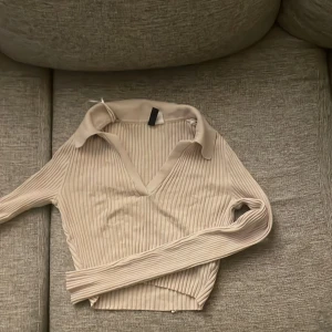 Beige ribbad långärmad tröja XS - Säljer en beige ribbad långärmad tröja från Divided. Tröjan har v-ringning, krage och är croppad i modellen. Perfekt för dig som gillar en stilren och trendig look. Passar till både jeans och kjol. Väldigt stretchig hade passat S & M också 