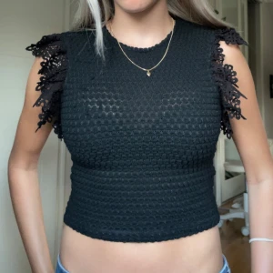Svart stickad topp med spets från Zara - Supersnygg svart stickad topp från Zara med croppad passform och korta fint stickade spets ärmar. I storlek S men skulle säga att xs också funkar. Superskön också. Tyvärr några trådar på framsidan som lossnat från tyget (vissas på sista bilden) men inget man tänker på och går säkert att ta bort enkelt.