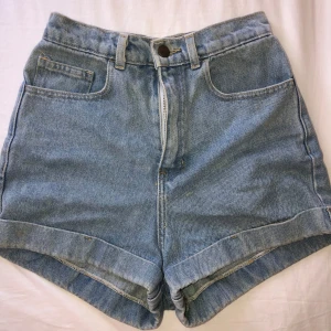Snygga jeansshorts American Apparel - Klassiska ljusblå jeansshorts från American Apparel med hög midja och uppvikta benslut. 