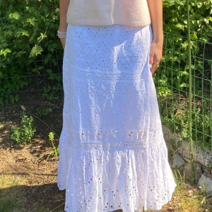 Vit långkjol volang - Superfin vit långkjol med detaljer och hålmönster. Kjolen har ett kortare inre lager som gör att kjolen inte blirh genomskinlig. Har sytts ihop en gång som ses på bild 4. Storlek 38 men jag upplever den mer som en 36.