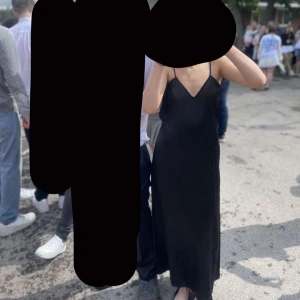 Svart långklänning med smala axelband - Snygg svart långklänning med smala axelband och v-ringning. Klänningen har en stilren och minimalistisk look med lätt glansigt material som ger en lyxig känsla. Perfekt för dig som gillar en enkel men elegant stil. (Bara använd 1 gång) klänningen är i storlek XS men skulle även passa en S