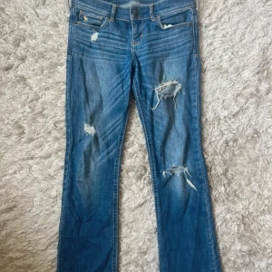 Blå bootcut jeans med slitningar - Snygga blå jeans med bootcut passform och slitna detaljer på både fram- och baksida. Midjemått rakt över är 34 och innerbenslängd är 71❤️