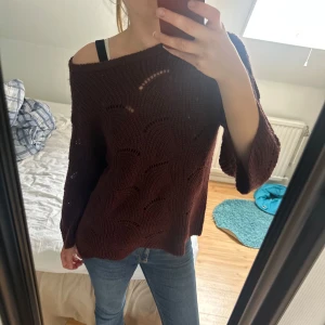 Mörk vinröd stickad offshoulder tröja - Säljer en mörk vinröd stickad tröja med offshoulder-look och snyggt hålmönster.