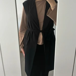 Svart ZARA väst/trench - Säljer denna supersnygga väst fran Zara. Har knappt använt den. Köpt i USA. Det tillkommer ett tygskärp som man kan ta bort.