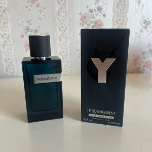 Yves Saint Laurent Y Eau de Parfum Intense - Y Eau de Parfum Intense från Yves Saint Laurent i en stilren, mörkblå glasflaska med silverdetaljer och svart texturerad kork. Flaskan rymmer 100 ml och kommer med originalkartong i matchande mörkblått med en stor silverfärgad Y-logga. En modern och maskulin doft.