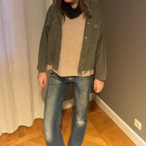 Grön jeansjacka - Säljer en grön jeansjacka med knappar framtill och två bröstfickor. Jackan har en avslappnad stil med fransiga kanter och är perfekt för en casual look. Passar bra till jeans och t-shirt.
