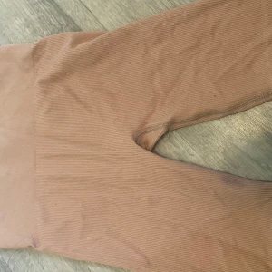 Ribbade bruna leggings i M - Säljer ett par ribbade leggings i en snygg brun nyans. De är stretchiga och bekväma med hög midja, perfekta för en chill vardagslook. Materialet är 87% polyamid och 13% elastan vilket gör dem mjuka och följsamma.