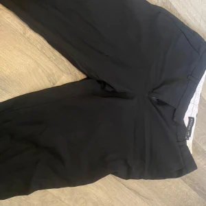 Svarta kostymbyxor från STOCKH LM - Svarta kostymbyxor från STOCKH LM i klassisk rak modell. Byxorna har hällor för bälte och stängs med dragkedja och knapp. Perfekta för en clean och stilren look, passar till både sneakers och boots.