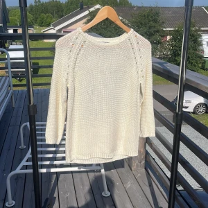 Vit stickad tröja från H&M BASIC XS - Vit stickad tröja från H&M BASIC i storlek XS. Tröjan har trekvartsärm, rund halsringning och dekorativa håldetaljer längs axlarna. Tillverkad i 100% akryl och har en klassisk, enkel look som passar perfekt till jeans eller kjol.