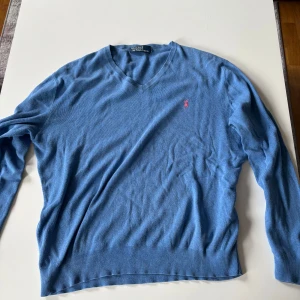 Blå v-ringad tröja från Polo Ralph Lauren - Blå v-ringad tröja från raplh lauren. Den är lite noppig och storleks lappen är avklippt men annars inga fel.