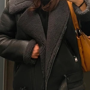 Svart skinnjacka med fuskpälsfoder - Säljer en svart skinnjacka med mjukt fuskpälsfoder och bred krage. Jackan har dragkedja, fickor med dragkedja och bältesdetalj nedtill. Perfekt för kyliga dagar och ger en cool look. Passar S