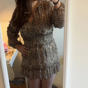 Leopardmönstrad klänning från Zara - Säljer en snygg leopardmönstrad klänning från Zara med långa ärmar och markerad midja. Klänningen har volangdetalj nertill och v-ringning framtill. Slutsåld överallt, skulle säga den passar strl L-S.💞
