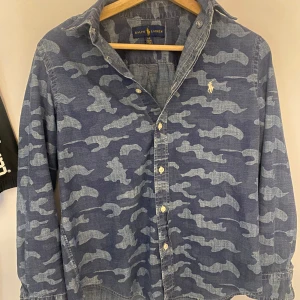 Ralph lauren skjorta  - Säljer nu en galet snygg camo Ralph lauren skjorta som tyvärr blivit för liten. Skick 10/10, Inga defekter alls. Jag skulle säga att den passar någon som är 165-170 beroende hur man vill att den ska sitta. Om ni undrar över något, ställ gärna frågor om mått osv så löser jag så snabbt som möjligt!👍🏻(priset ej hugget i sten) 