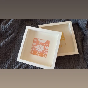 Vita fyrkantiga ramar med blommigt motiv - Två vita fyrkantiga ramar från IKEA med blommiga motiv. Ramarna är tillverkade i trä och har en modern, stilren design. Perfekt för att ge rummet en färgklick och personlig touch.