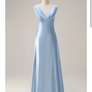 Ljusblå balklänning i satin - Elegant ljusblå långklänning i satin med djup v-ringning och breda axelband. Klänningen har en figurnära passform upptill och faller mjukt ner mot golvet. Perfekt för bal eller festliga tillfällen. Köpt från Zapaka och är endast testad. Säljer då jag hittat en annan balklänning. Köpt för 1110kr