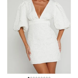 Vit kortklänning med puffärmar från Showpo - Superfin vit kortklänning från Showpo med djup v-ringning och stora puffärmar. Klänningen har en strukturerad yta och markerad midja som ger en snygg siluett. Perfekt för somriga tillfällen och student.