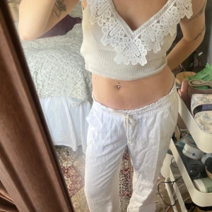 Vit croppad linnetopp med spetsdetaljer - Säljer en vit croppad linnetopp med breda axelband och vacker spets  längs den djupa v-ringningen. Toppen är från ZARA i st S Toppen är ribbad och har en figurnära passform, perfekt för varma dagar. Säljer då jag inte tycker om croppafe toppar🤍🤎