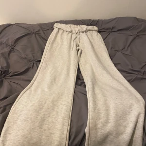 Grå mjukisbyxor med dragsko - Säljer ett par ljusgrå mjukisbyxor med bred resår i midjan och dragsko. Byxorna har en loose passform och är perfekta för en avslappnad stil. Mjukt material som känns skönt mot huden.