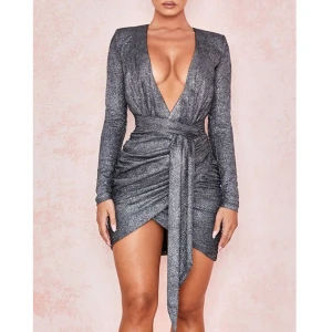 Glittrig silver klänning från House of CB - Supersnygg kort klänning i glittrigt silvermaterial från House of CB. Har en djup v-ringning och markerad midja med knytband. Långärmad och figurnära passform med rynkade detaljer framtill och baktill. Använd endast gång på NYÅR och är i princip ny. Har inga fel eller defekter. Orginalpris 179$ = ca 1790kr. Pris kan diskuteras vid snabb affär. 