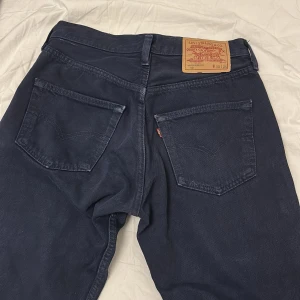 Mörkblå Levis 501 jeans - Klassiska mörkblå Levis 501 jeans med raka ben och fem fickor. Byxorna har knappgylf, Levis-lapp bak i midjan och röd Levis-tagg på bakfickan. Perfekta för en tidlös och avslappnad stil. Storlek W30 L34, Aldrig använda! Priset är som alltid schysst och inte hugget i sten🤩☺️😀