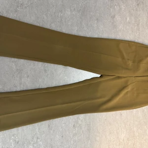 Khaki kostymbyxor från ONLY - Snygga khaki kostymbyxor från ONLY med elastisk midja, dragkedja och knapp framtill. Byxorna har raka ben och är perfekta för en stilren look. Sköna och lätta att matcha med olika toppar. Öppen för bud!💕