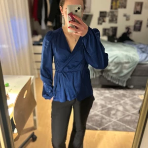 Mörkblå blus från  - Säljer en mörkblå blus med långa puffärmar och markerad midja. 