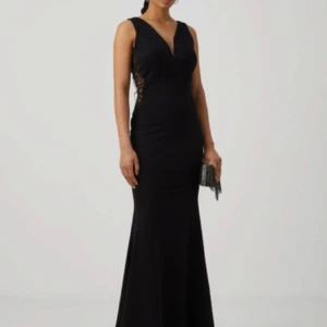 Svart långklänning med spets och v-ringning - Elegant svart långklänning med v-ringad spets upptill och breda axelband. Klänningen har figurnära passform upptill och faller snyggt längs kroppen. Perfekt för bal eller fest. Dragkedja bak och diskreta spetsdetaljer på sidorna. Använd endast en gång på min bal 2023🤍
