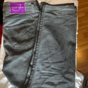 Jacob cohen 622 jeans - Säljer ett par grå jeans från Jacob Cohen i modellen 622 i storleken W31, fint skick med endast lite slitage på några sömmar men påverkar inte alls jeansen därav priset. med lila patch och snygga kontrastsömmar. Byxorna har klassisk femficksdesign och raka ben. Perfekta för dig som gillar stilrena och exklusiva jeans. En elegant grå färg som går att matcha med det mesta. Priset är ej hugget i sten