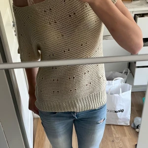 Beige stickad topp från Vero Moda - Säljer en beige stickad topp från Vero Moda. Tröjan har korta ärmar, bred halsringning och ett hålmönster över hela plagget. Nästan helt oanvänd och säljs inte längre storlek s.