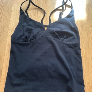 Svart linnetopp från BikBok - Säljer en svart linnetopp från BikBok med smala axelband och enkel design. Perfekt att matcha med jeans eller kjol för en stilren look. 