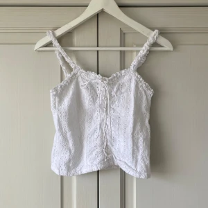 Vit broderad linnetopp med knyt - Otrolig vit topp perfekt nu till sommaren eller till fest!! Såå söt med broderi och coola snörningsdetaljer. Uppskattar storleken till xs. Skriv vid frågor eller tryck på köp nu!💕