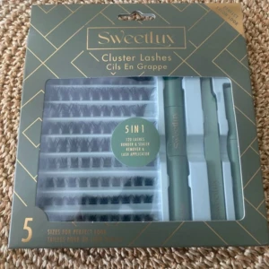 Sweetlux Cluster Lashes 5-i-1 kit - Sweetlux Cluster Lashes 5-i-1 kit med 120 individuella lösögonfransar i olika storlekar, samt remover, sealer och applikator. Perfekt för att skapa fylliga och naturliga fransar hemma. Förpackningen är grön och guldig.