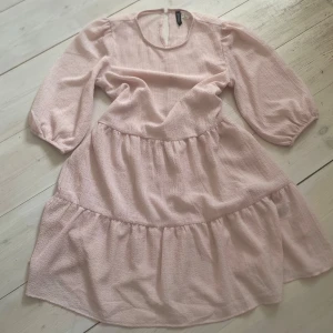 Ljusrosa klänning från H&M  - Supersöt ljusrosa klänning från H&M  i storlek XS. Klänningen har trekvartsärmar, rund halsringning och volangdetaljer i kjolen. Medföljer ett matchande ljusrosa underlinne. Perfekt för vår och sommar!