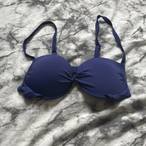 Mörkblå bikini - Säljer en mörkblå bikini-bh med justerbara axelband och vadderade kupor. Klassisk modell med enkel knäppning bak. Perfekt för strand eller poolhäng i sommar!