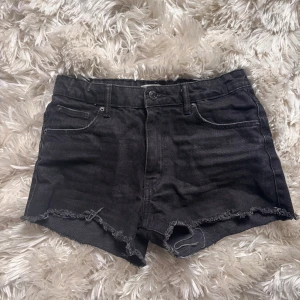 Svarta jeansshorts från Gina Tricot - Snygga svarta jeansshorts från Gina Tricot med fransig kant nertill. Perfekta för varma dagar och enkla att matcha med olika toppar. Lågmidjade.