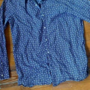 Mönstrad blå skjorta från Hilfiger Denim - Säljer en blå långärmad skjorta från Hilfiger Denim med vitt geometriskt mönster och knappar framtill. Skjortan har klassisk krage och är perfekt för dig som gillar en stilren men ändå unik look.