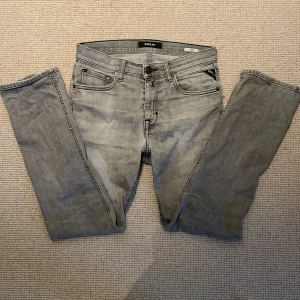 Ljusgrå replay jeans  - Säljer ett par ljusgrå jeans från Replay med klassisk femficksdesign och dragkedjegylf. Jeansen har raka ben och diskreta sömmar, perfekta för en clean look. Märkeslapp bak i midjan och snygga detaljer vid fickorna.