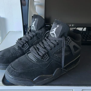 Svarta Nike Air Jordans sneakers - Säljer ett par helsvarta Nike Air Jordans sneakers med klassisk Jumpman-logga på plösen och hälen. Skorna har snörning, meshpaneler på sidorna och detaljer i syntetmaterial. Perfekta för dig som gillar stilrena och sportiga sneakers.